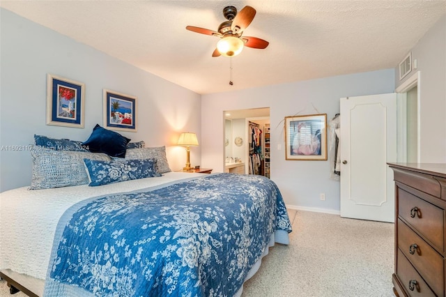 carpeted bedroom featuring ceiling fan, a textured ceiling, a closet, and a walk in closet