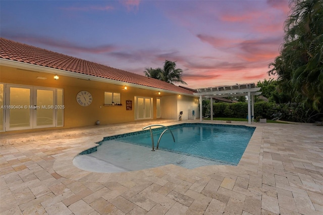 pool at dusk featuring a pergola, a patio area, and french doors