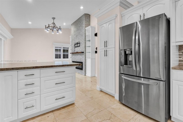 kitchen with stainless steel refrigerator with ice dispenser, hanging light fixtures, dark stone counters, decorative backsplash, and white cabinets