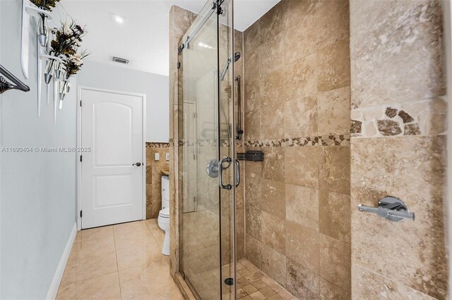 bathroom with tile patterned flooring, a shower with shower door, and toilet