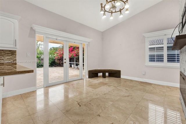 unfurnished dining area with lofted ceiling, a notable chandelier, and french doors