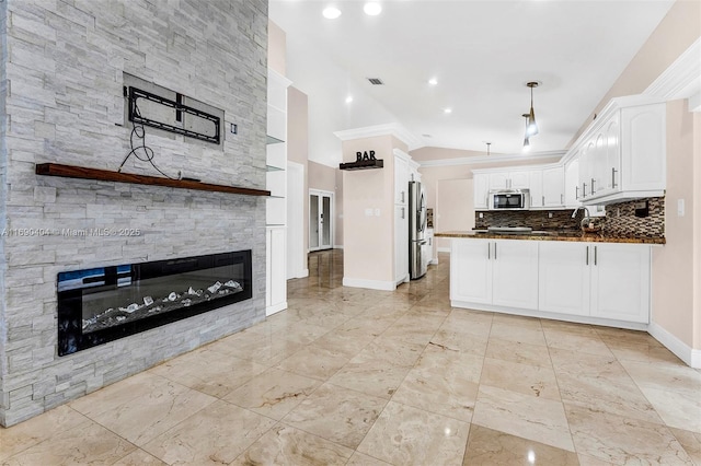 kitchen featuring appliances with stainless steel finishes, tasteful backsplash, a fireplace, white cabinets, and kitchen peninsula