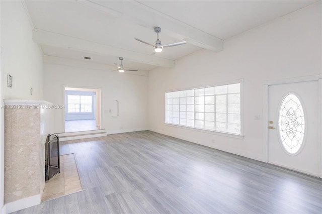 unfurnished living room featuring lofted ceiling with beams, a wealth of natural light, ceiling fan, and light hardwood / wood-style flooring