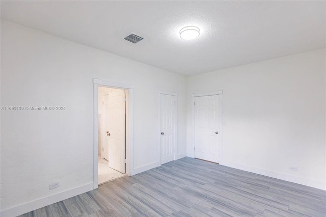 spare room featuring light hardwood / wood-style floors and a textured ceiling