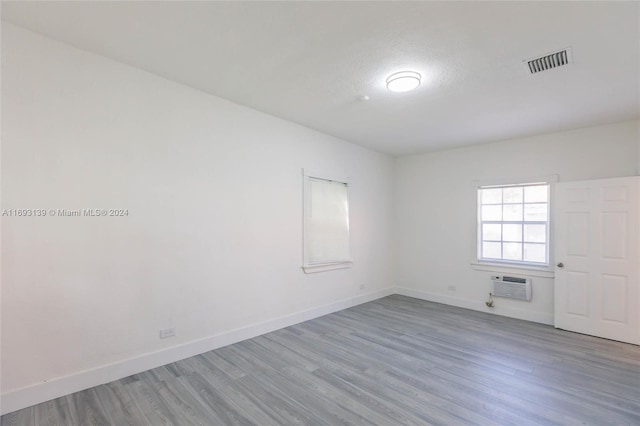 spare room featuring hardwood / wood-style floors and a wall mounted air conditioner