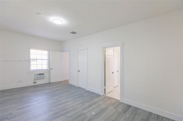 unfurnished room featuring a wall mounted AC and light hardwood / wood-style flooring