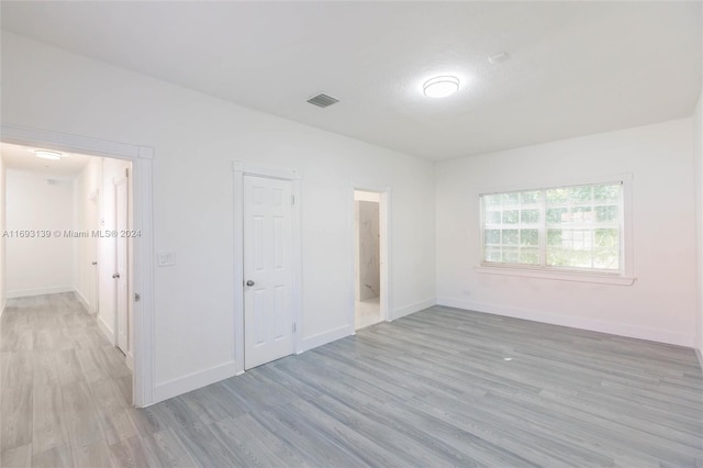 unfurnished bedroom featuring connected bathroom, a closet, and light hardwood / wood-style flooring