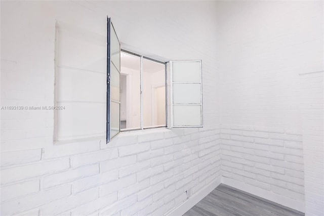 unfurnished room with wood-type flooring and brick wall