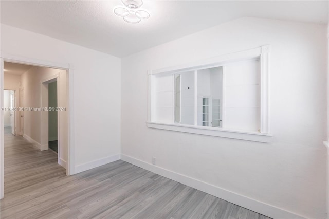 empty room featuring light wood-type flooring and lofted ceiling