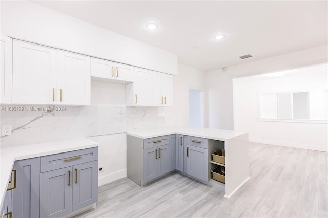 kitchen with white cabinets, light hardwood / wood-style flooring, backsplash, and gray cabinetry