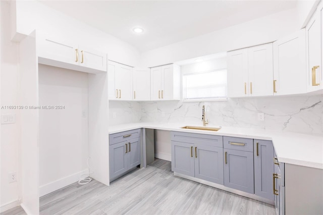 kitchen featuring white cabinetry, light hardwood / wood-style floors, sink, and tasteful backsplash