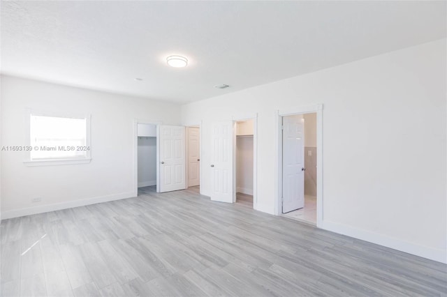 unfurnished bedroom with a closet, light wood-type flooring, and a spacious closet