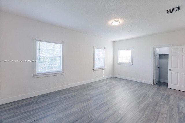 spare room with wood-type flooring, a healthy amount of sunlight, and a textured ceiling