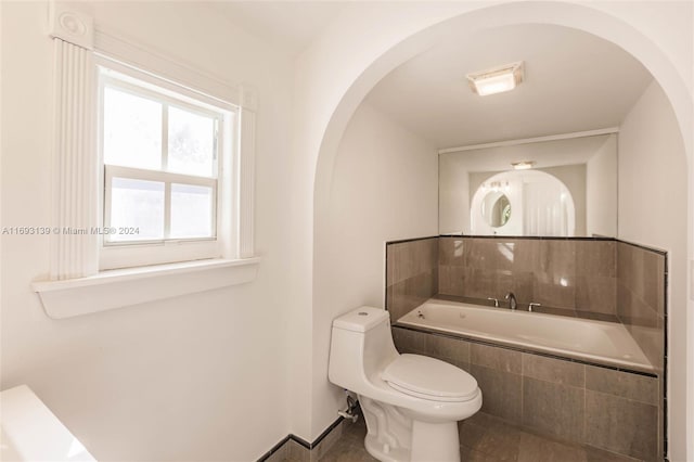 bathroom with toilet, tile patterned floors, and tiled tub