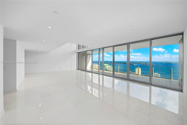 tiled spare room with a wall of windows and a water view