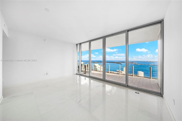 unfurnished room with expansive windows, a water view, and a healthy amount of sunlight