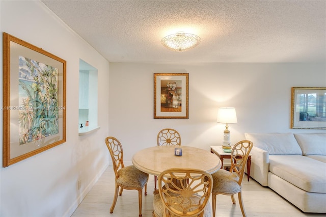 dining area featuring light hardwood / wood-style flooring and a textured ceiling