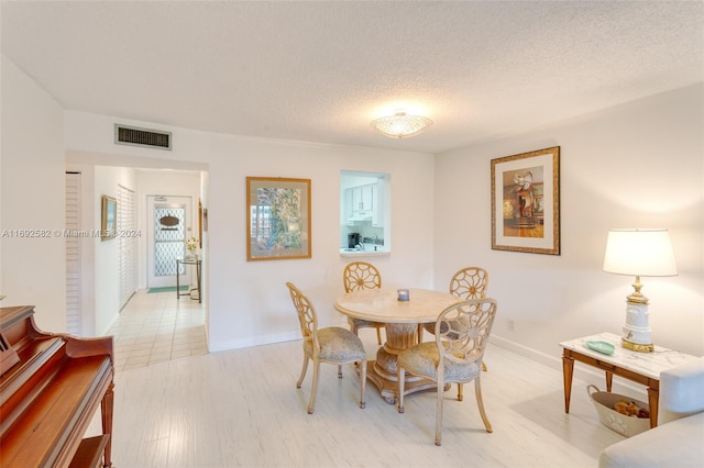 dining room featuring light wood-type flooring and a textured ceiling