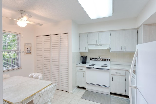 kitchen featuring decorative backsplash, a textured ceiling, ceiling fan, a skylight, and white appliances