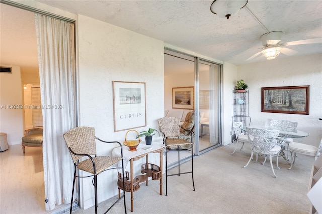 interior space with ceiling fan, a textured ceiling, and light colored carpet