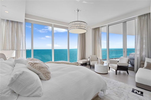 bedroom featuring wood-type flooring, multiple windows, access to exterior, and a water view