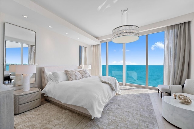 bedroom with light wood-type flooring, access to exterior, a chandelier, and a water view