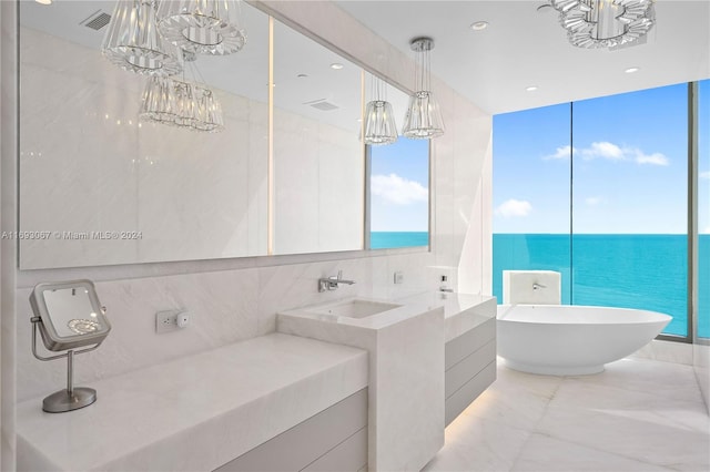 bathroom featuring tile walls, vanity, a water view, and a tub