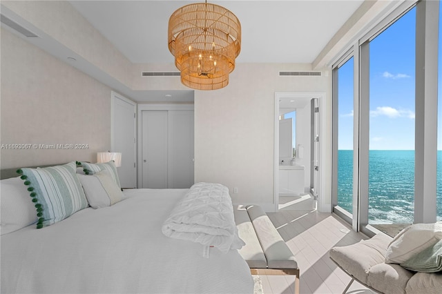 bedroom with ensuite bath, a water view, and a notable chandelier