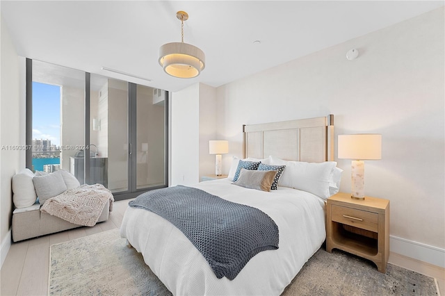 bedroom with light hardwood / wood-style floors and a water view