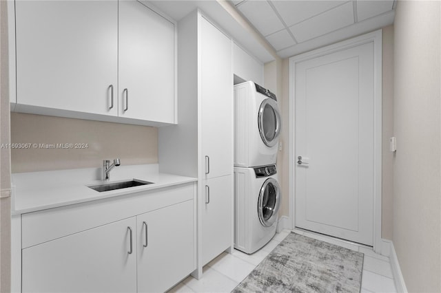 laundry area with stacked washer / dryer, cabinets, sink, and light tile patterned flooring