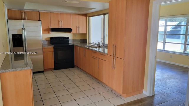 kitchen with electric range, stainless steel fridge, sink, and light hardwood / wood-style flooring