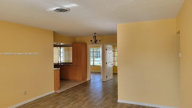 corridor featuring light hardwood / wood-style floors, a textured ceiling, and an inviting chandelier