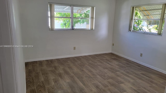 empty room with a healthy amount of sunlight and dark hardwood / wood-style floors