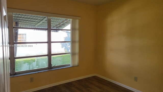 unfurnished room featuring a wealth of natural light and dark wood-type flooring