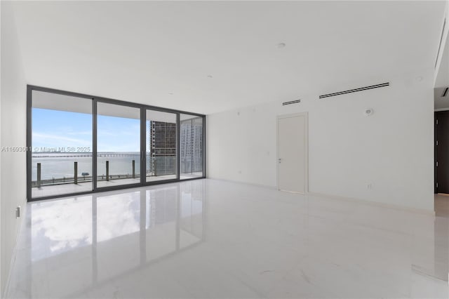 empty room featuring a water view and expansive windows