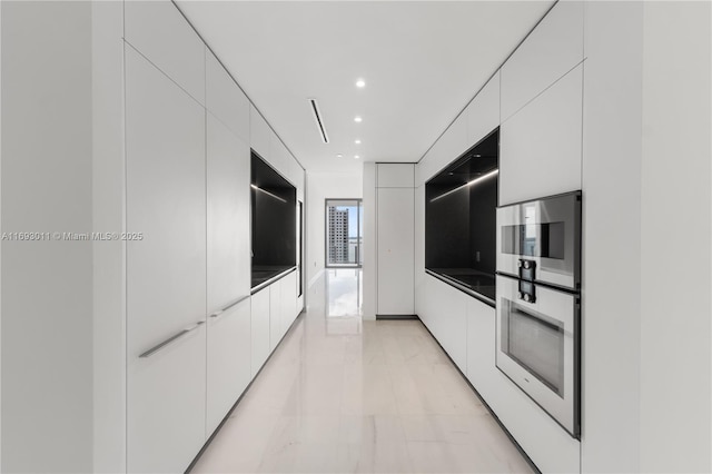 kitchen featuring wall oven and white cabinetry