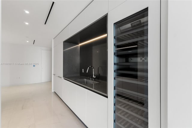 kitchen with white cabinetry, sink, and wine cooler