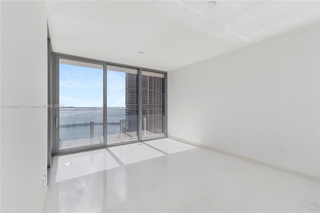 unfurnished room featuring expansive windows and a water view