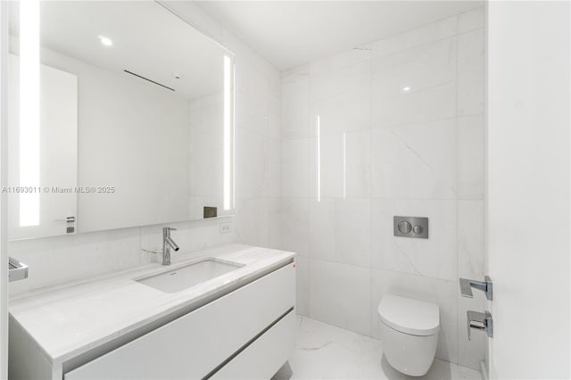 bathroom featuring vanity, toilet, and tile walls