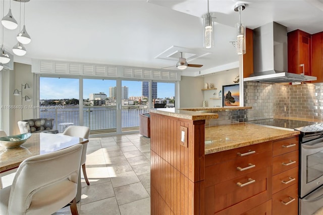 kitchen with a wealth of natural light, wall chimney exhaust hood, and decorative light fixtures