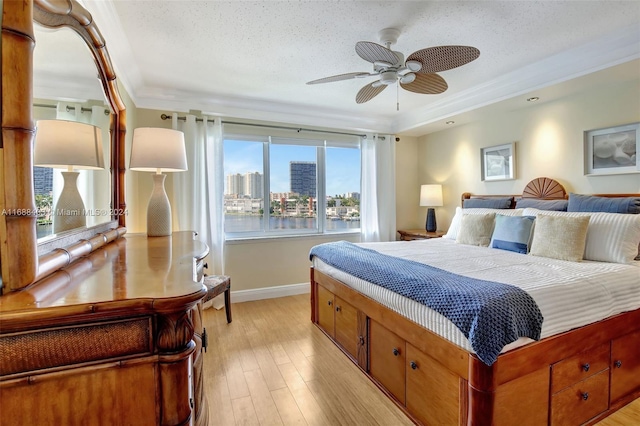 bedroom featuring light hardwood / wood-style floors, ceiling fan, a textured ceiling, and crown molding