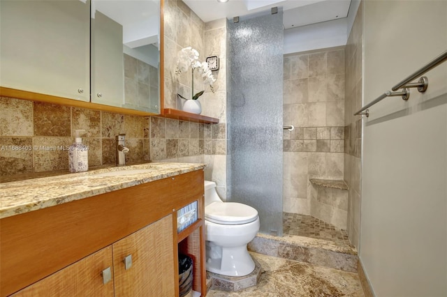 bathroom featuring tiled shower, toilet, vanity, and backsplash