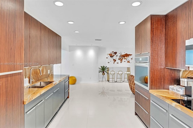 kitchen featuring stainless steel oven, sink, and black electric stovetop