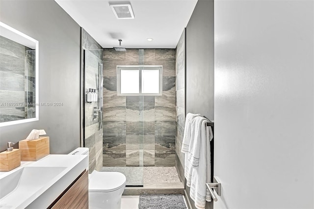 bathroom featuring vanity, toilet, and tiled shower