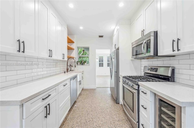 kitchen with backsplash, stainless steel appliances, white cabinetry, and beverage cooler