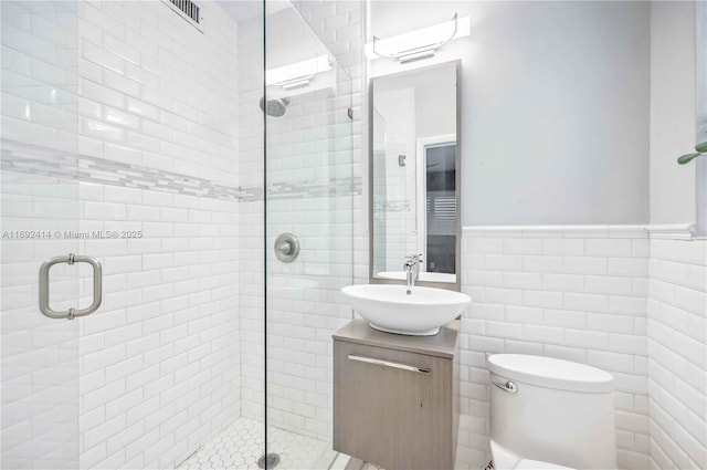 bathroom featuring vanity, toilet, walk in shower, and tile walls