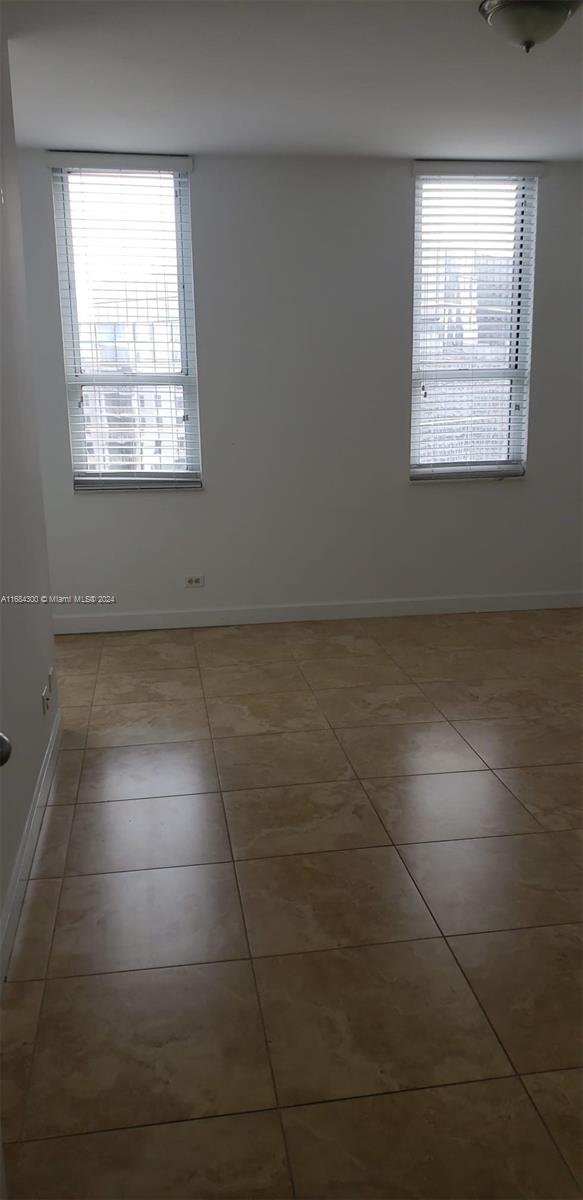 empty room featuring tile patterned floors and a healthy amount of sunlight