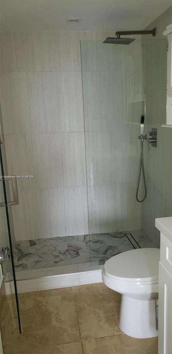 bathroom with tiled shower, vanity, and toilet