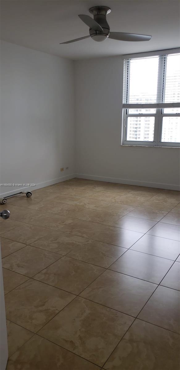 tiled spare room with ceiling fan