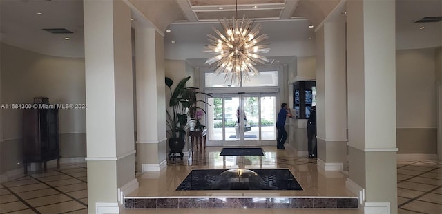 foyer entrance with a chandelier, light tile patterned floors, and french doors